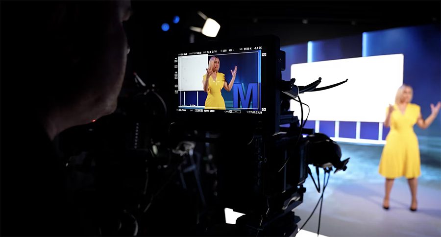 Woman in yellow dress speaking to the camera for a video production shoot